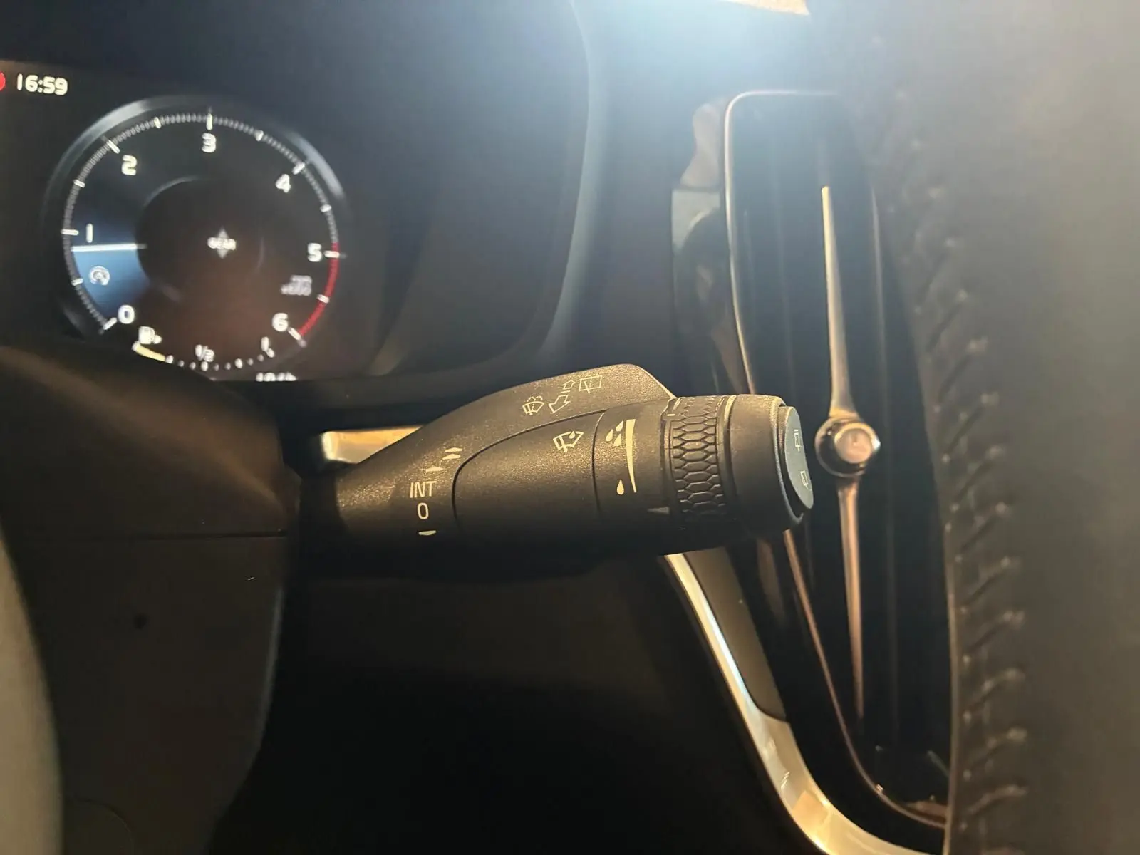 Gros plan sur la commande d’essuie-glace à gauche du volant dans l’habitacle noir du Volvo V60 blanc de 2020.