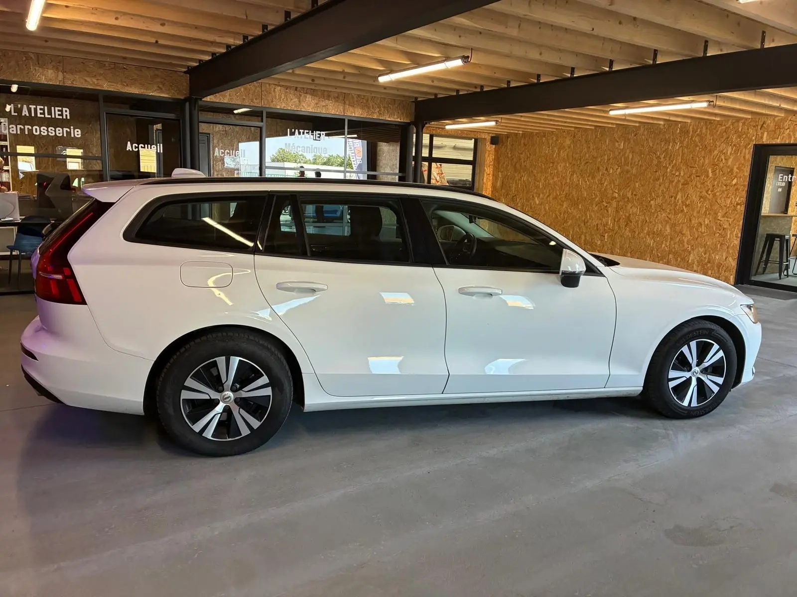Vue de profil côté gauche d'un Volvo V60 blanc de 2020, break 5 portes avec jantes alliage et intérieur noir visible.