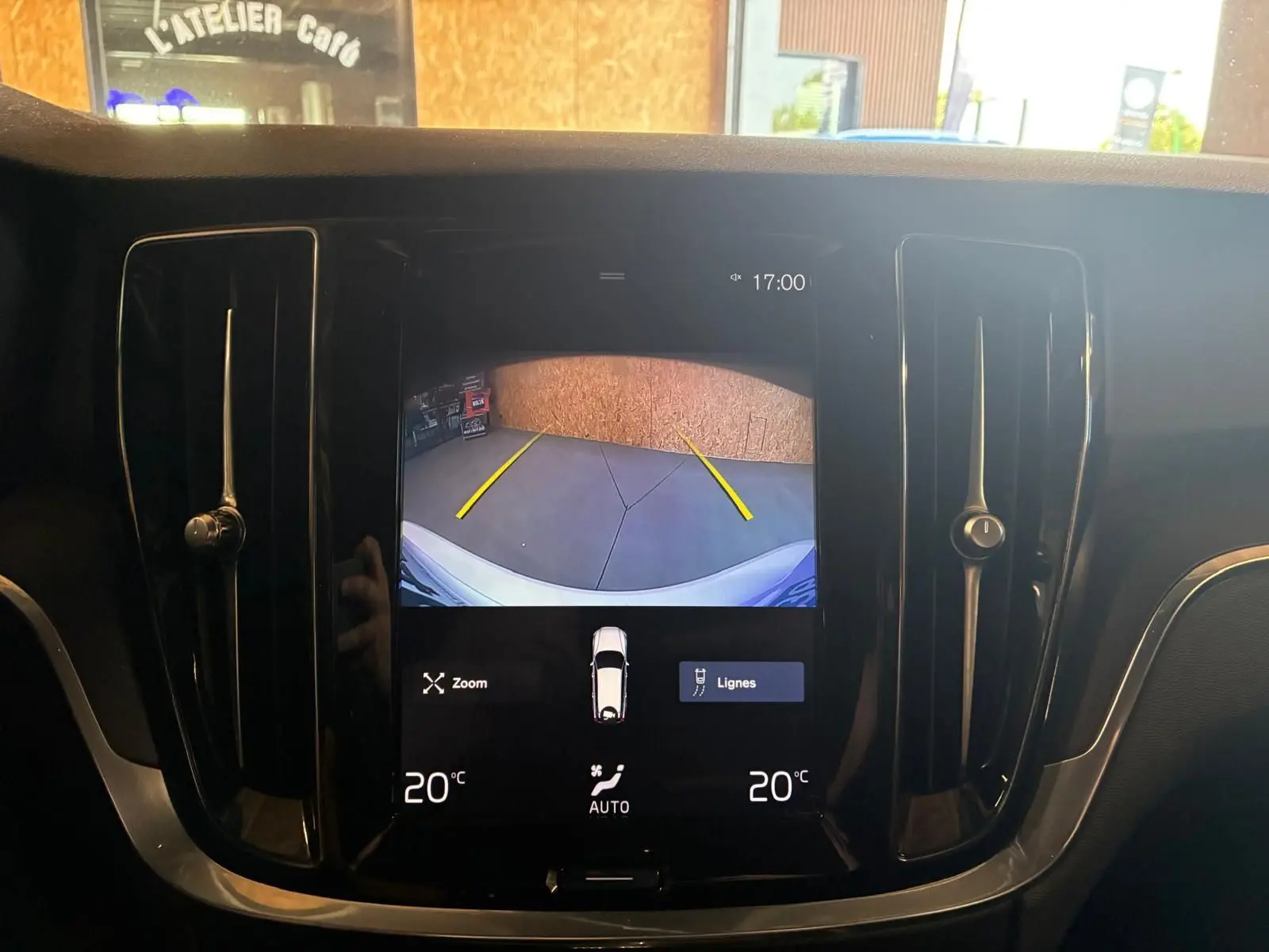 Vue rapprochée de l'écran central noir affichant la caméra de recul d'une Volvo V60 blanche, avec ventilation latérale visible.