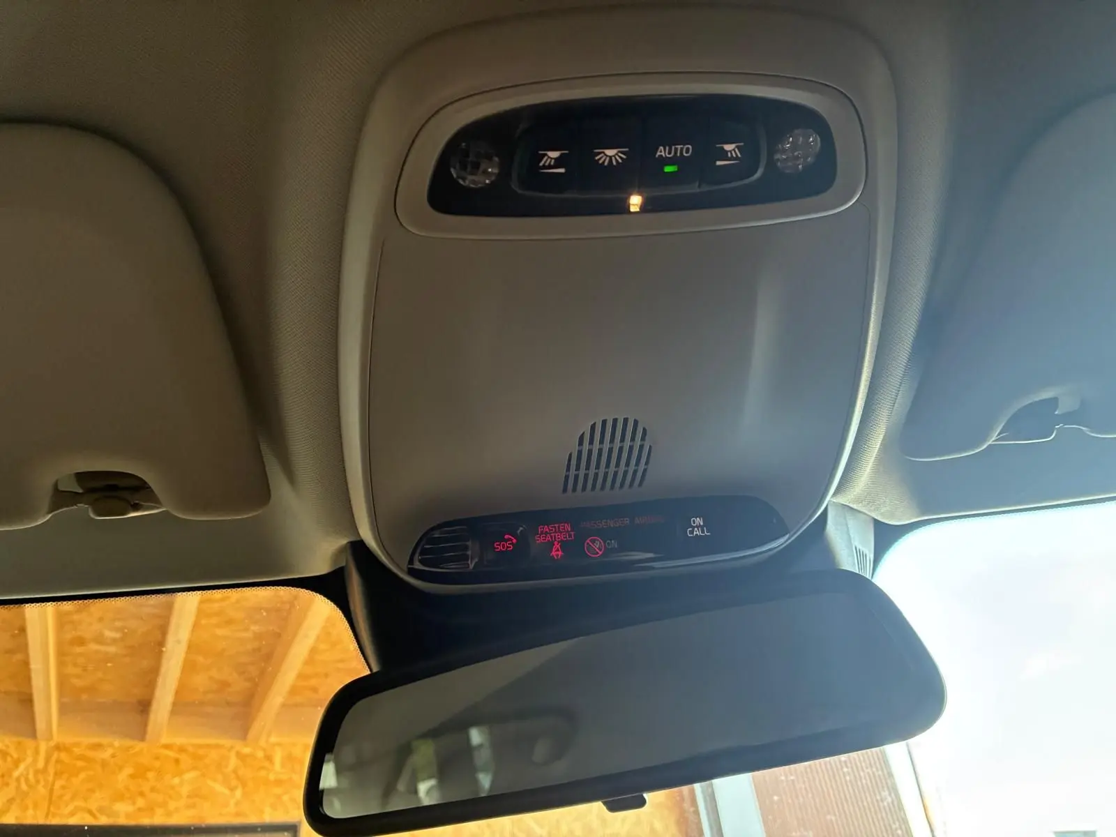 Vue intérieure en plongée du plafonnier gris avec commandes d’éclairage et rétroviseur intérieur d’une Volvo V60 blanche.