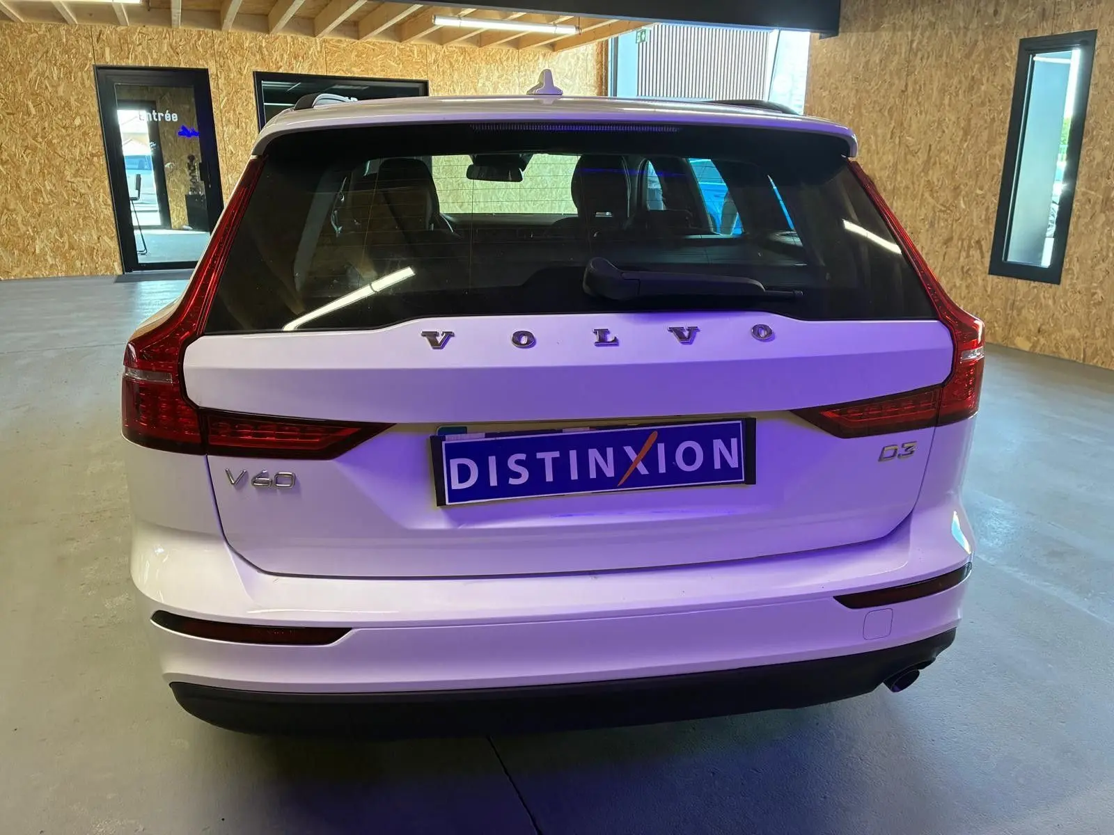 Vue arrière d'un Volvo V60 D3 blanc 2020 avec feux arrière LED et plaque d'immatriculation Distinxion visible.