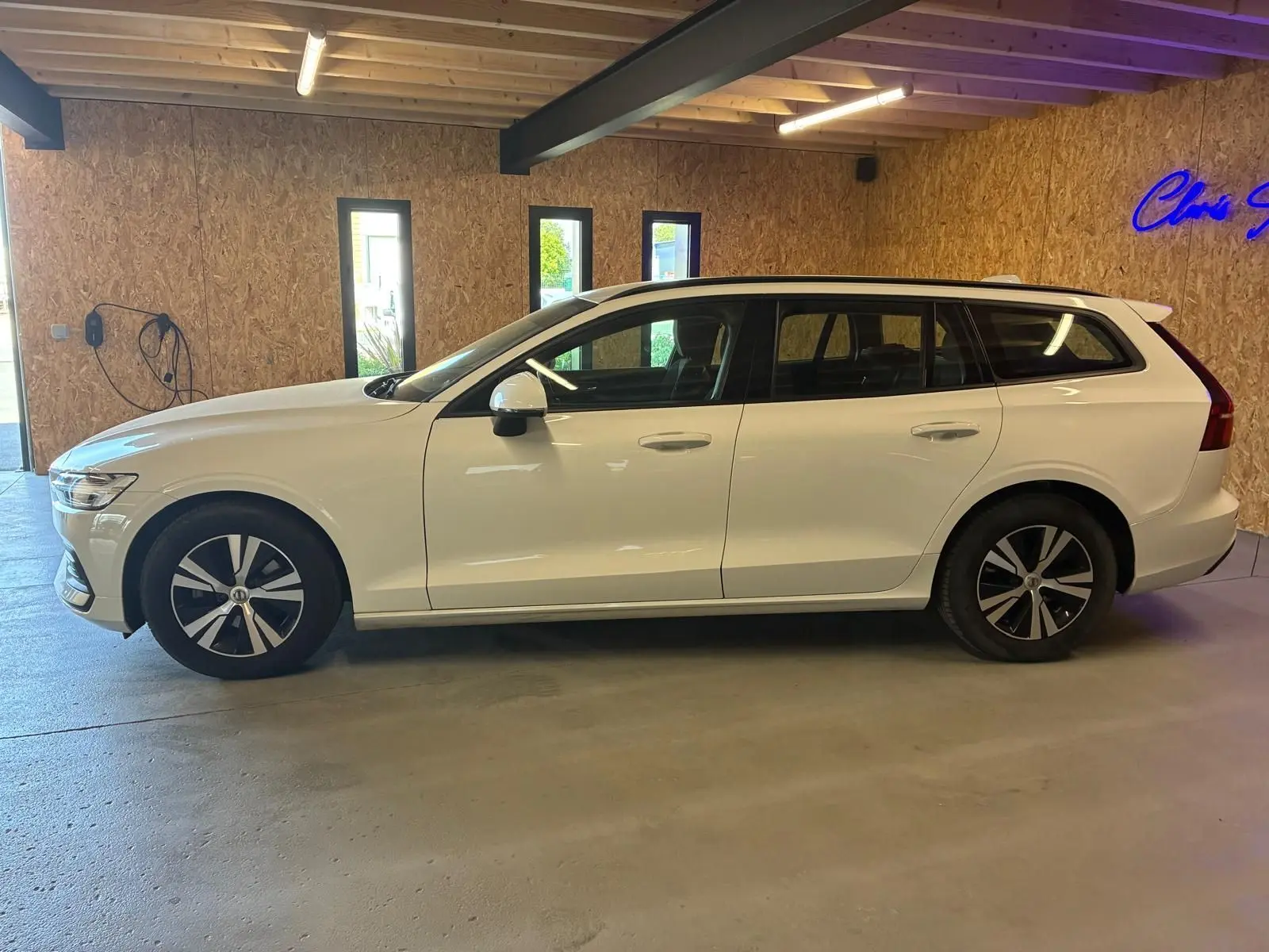 Vue de profil côté gauche d'un Volvo V60 D3 2.0 blanc, break 5 portes, stationné en intérieur.