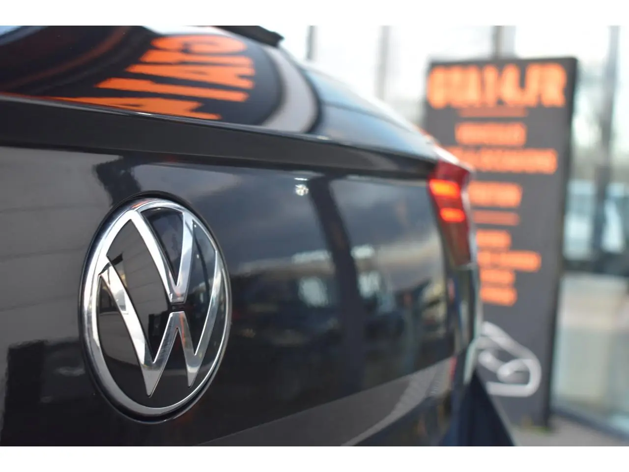 Gros plan sur l'arrière droit d'un Volkswagen T-Roc 2025 noir métallisé avec logo VW et feu arrière LED allumé.
