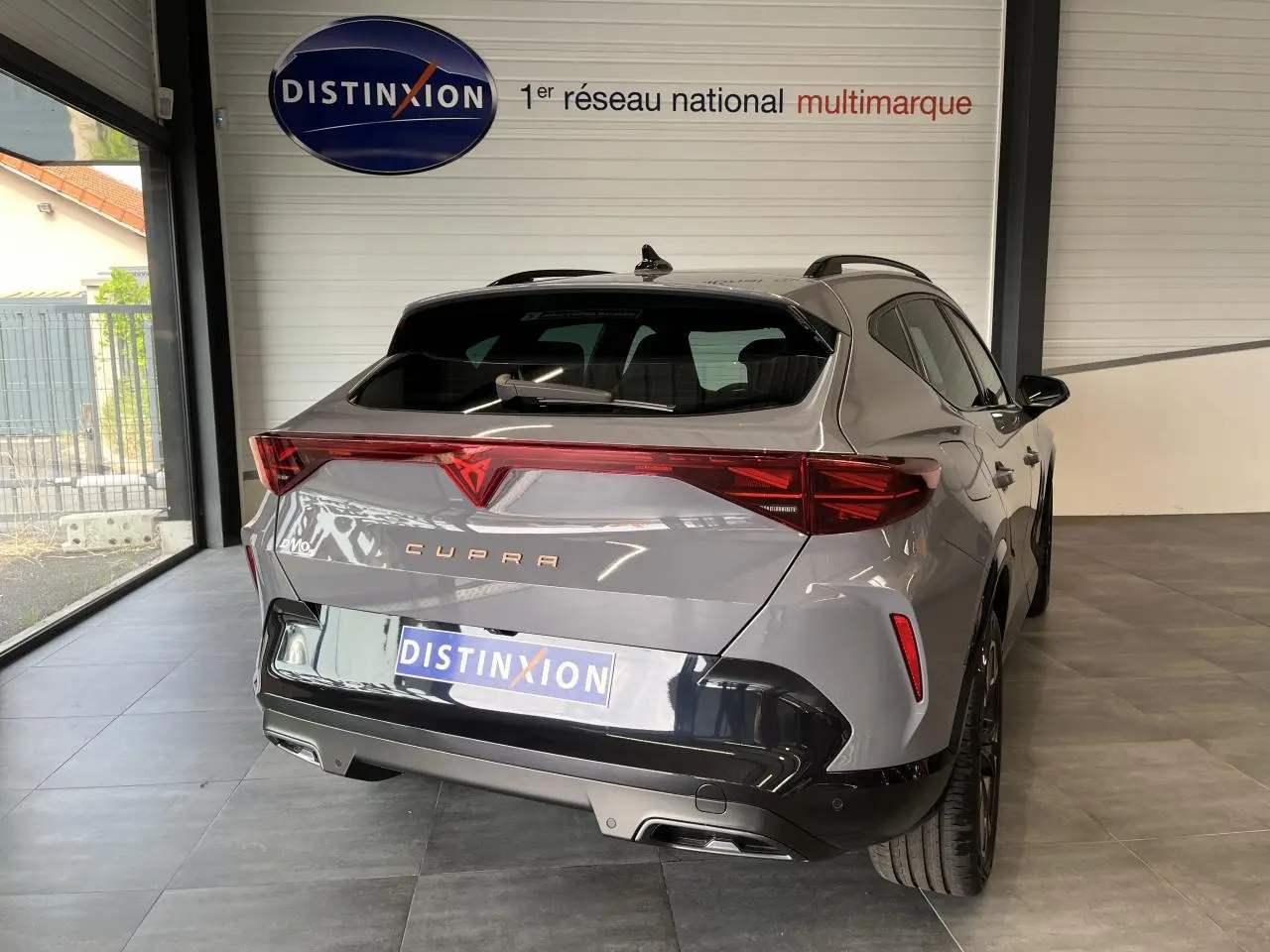 Vue 3/4 arrière droite d'un CUPRA Formentor gris clair avec signature lumineuse arrière Tri-LED et double sortie d'échappement noire.