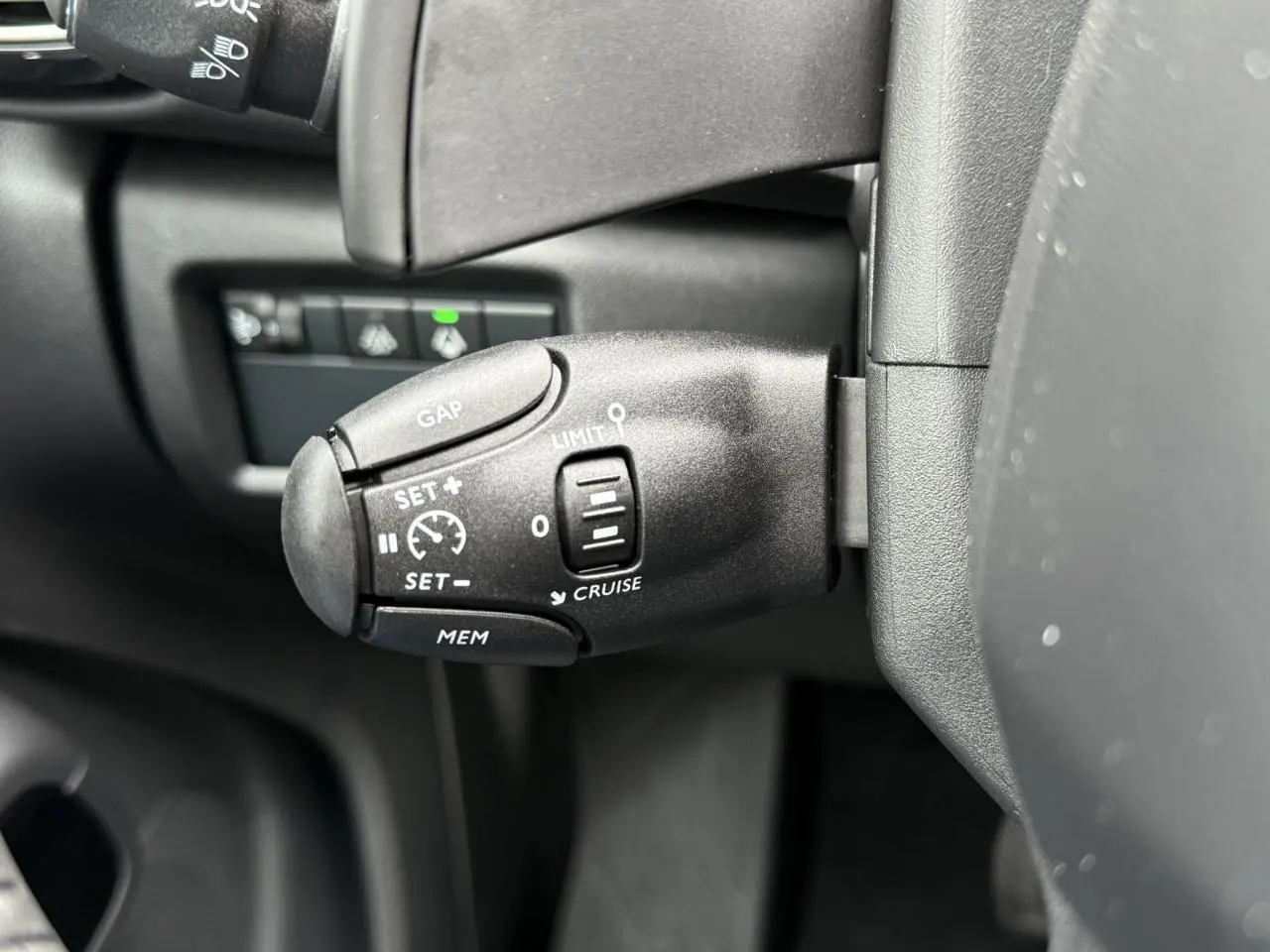 Gros plan sur la commande de régulateur de vitesse noir mat à gauche du volant dans l'habitacle du Citroën C5 Aircross.