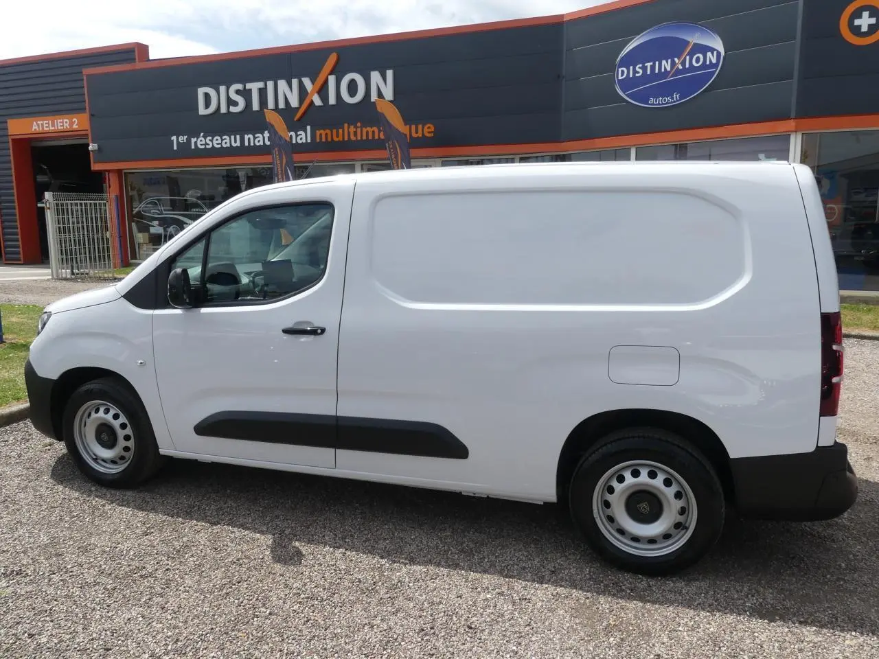 Peugeot Partner XL blanc vu de profil côté gauche, fourgon utilitaire avec protections noires sur les portières.