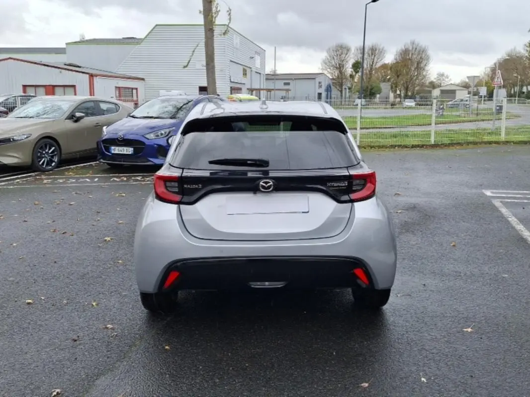 Vue arrière d'une Mazda2 hybride argent 2022 avec feux arrière reliés par une bande noire distinctive.