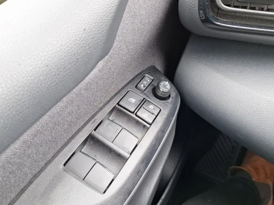 Gros plan sur les commandes des vitres et rétroviseurs côté gauche de la Mazda2 Hybrid 2022 avec intérieur gris.