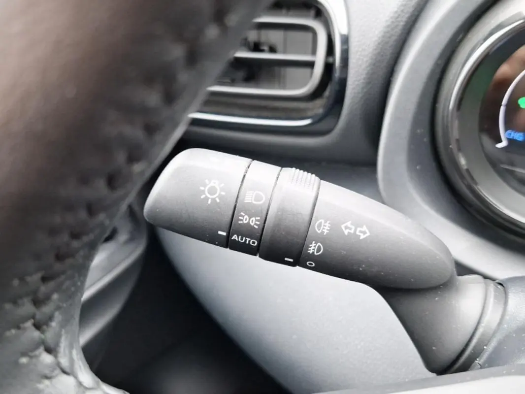 Commande des feux en gros plan à gauche du volant d'une Mazda2 hybride argent 2022, avec indication auto et phares antibrouillard.