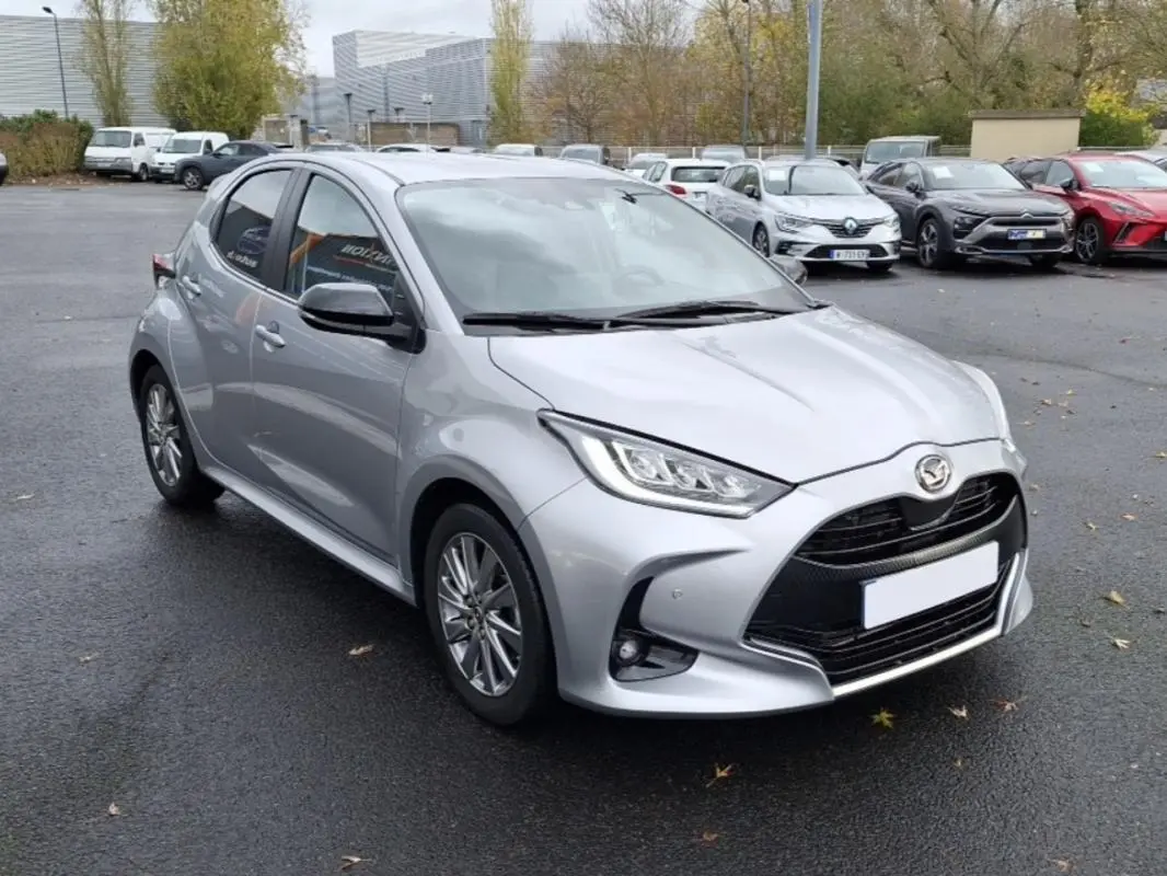 Vue 3/4 avant d'une Mazda2 hybride argent 2022 avec calandre noire et phares LED distinctifs.