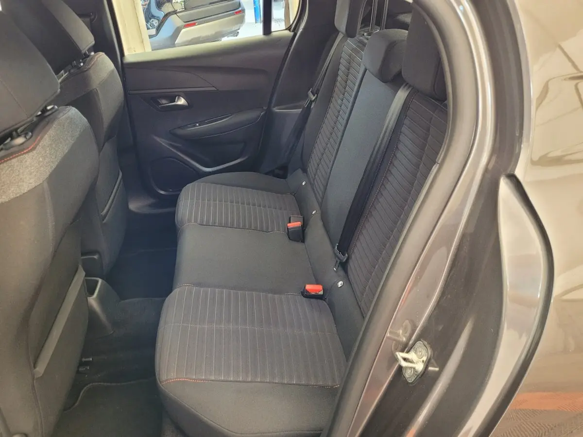 Vue côté droit de l'habitacle arrière gris foncé d'une Peugeot 208 BlueHDi 100 S&S Active Pack 2023 avec sièges tissu rayés.