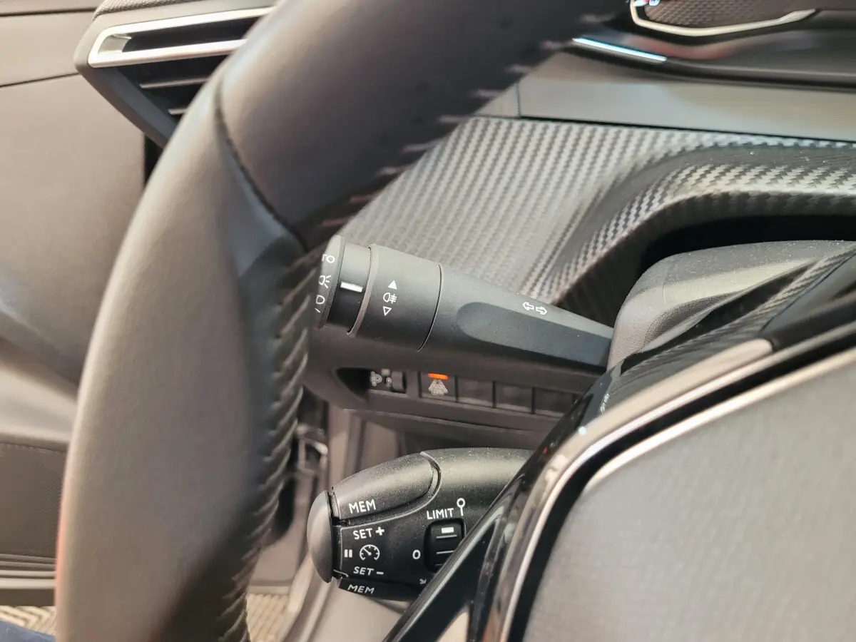 Gros plan sur le volant cuir et commandes au volant de la Peugeot 208 gris foncé version BlueHDi 100 S&S Active Pack 2023.