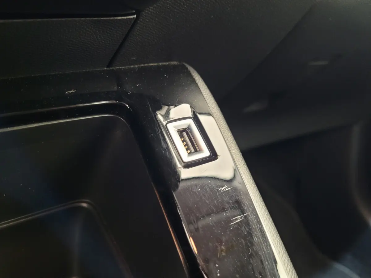 Gros plan sur un port USB intégré dans la console centrale noire d'une Peugeot 208 gris foncé 2023.