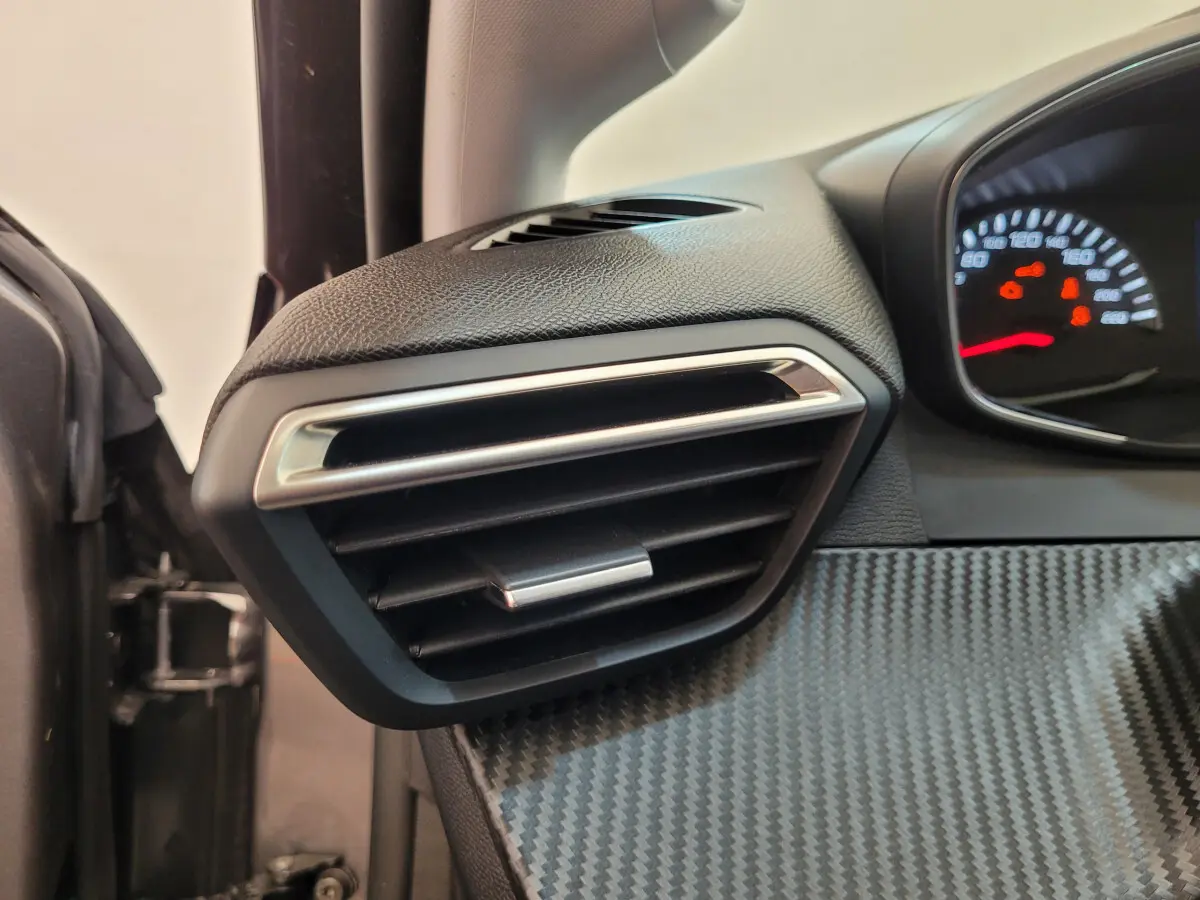 Gros plan sur la sortie d’air côté gauche du tableau de bord gris foncé de la Peugeot 208 2023 Active Pack.