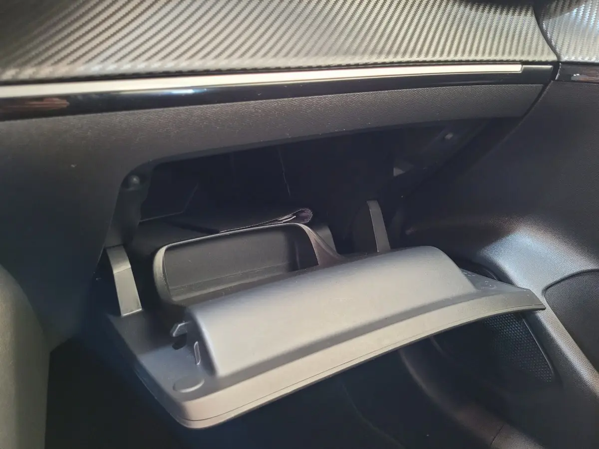 Gros plan sur la boîte à gants ouverte du Peugeot 208 gris foncé, montrant le tableau de bord et la finition intérieure.