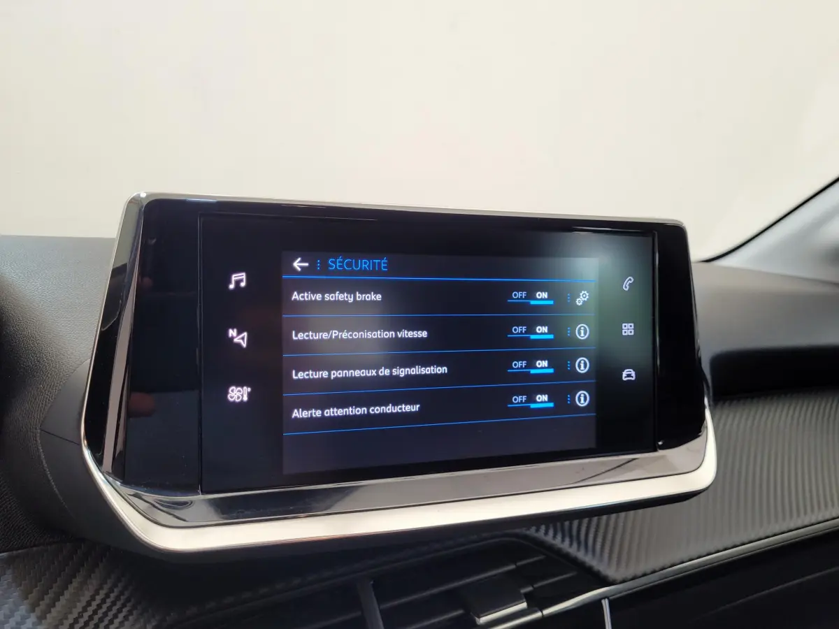 Écran tactile central affichant les options de sécurité dans l'habitacle d'une Peugeot 208 gris foncé 2023.