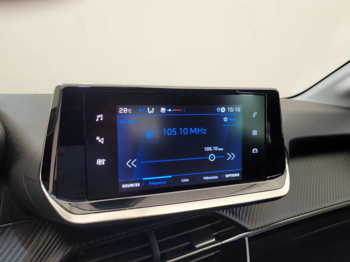 Écran tactile central de la Peugeot 208 gris foncé, affichant la radio FM à 105.10 MHz en intérieur.