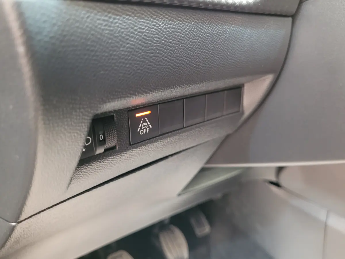 Gros plan sur le tableau de bord côté gauche du Peugeot 208 gris foncé, avec bouton d'alerte de franchissement de ligne activé.