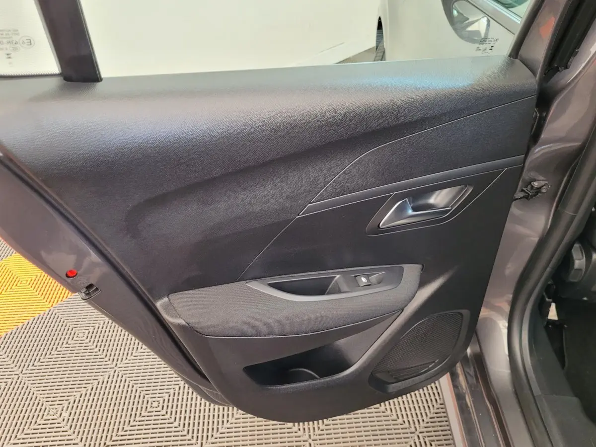 Vue rapprochée de la porte arrière droite gris foncé de la Peugeot 208 2023 avec commande de vitre et haut-parleur intégré.