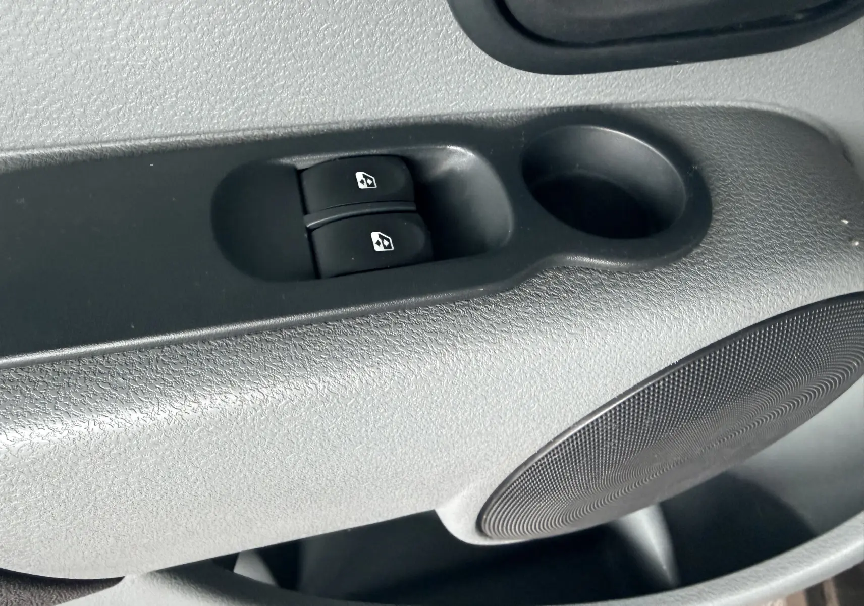Gros plan sur les commandes de lève-vitres électriques côté conducteur d’un Renault Modus beige, intérieur gris noir.