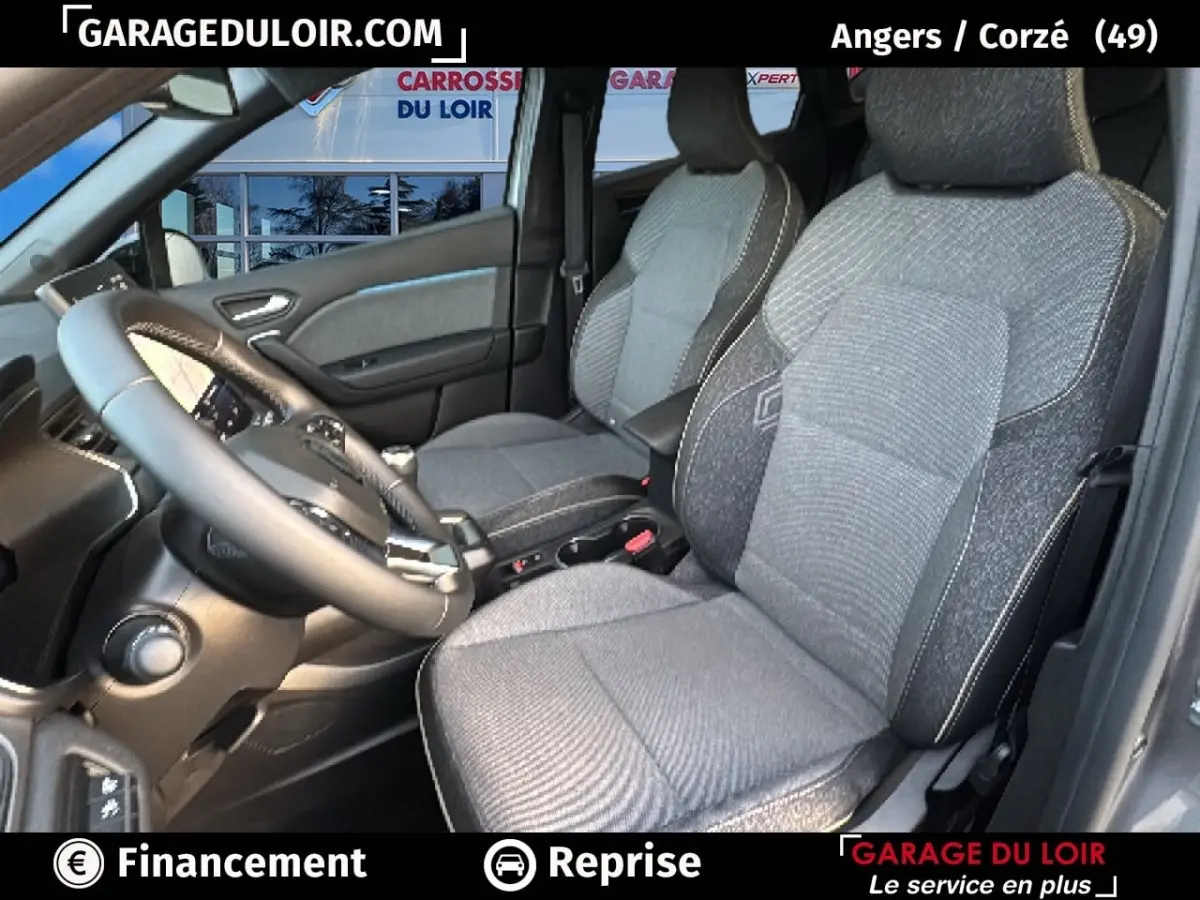 Vue intérieure côté conducteur du Renault Captur 2025 gris foncé, montrant les sièges en tissu et le volant multifonction.