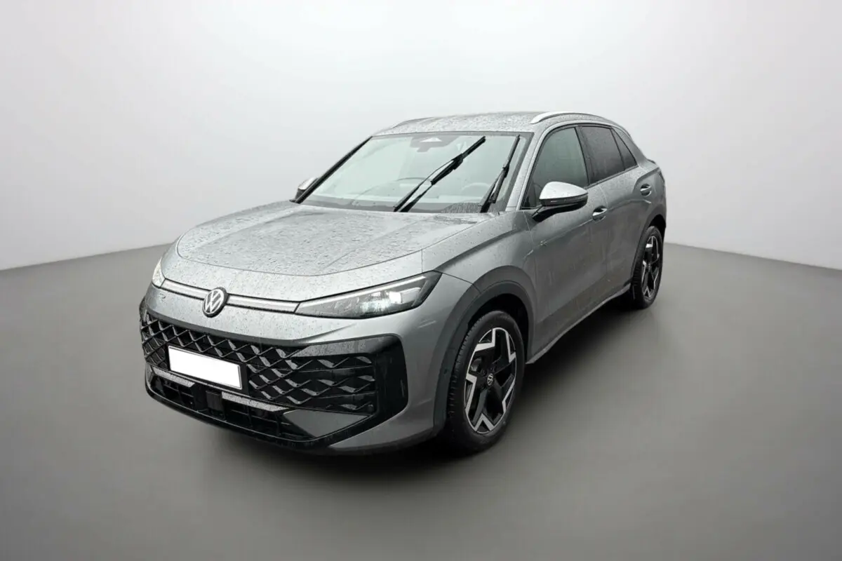 Volkswagen T-Roc gris loup en 3/4 avant droit, avec jantes alu noires et toit surélevé sous pluie légère.