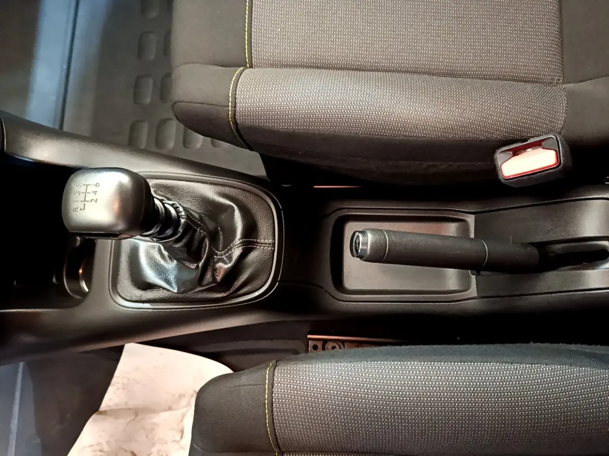 Vue plongeante sur la console centrale d'une Citroën C3 blanche, montrant levier de vitesse manuel et frein à main.
