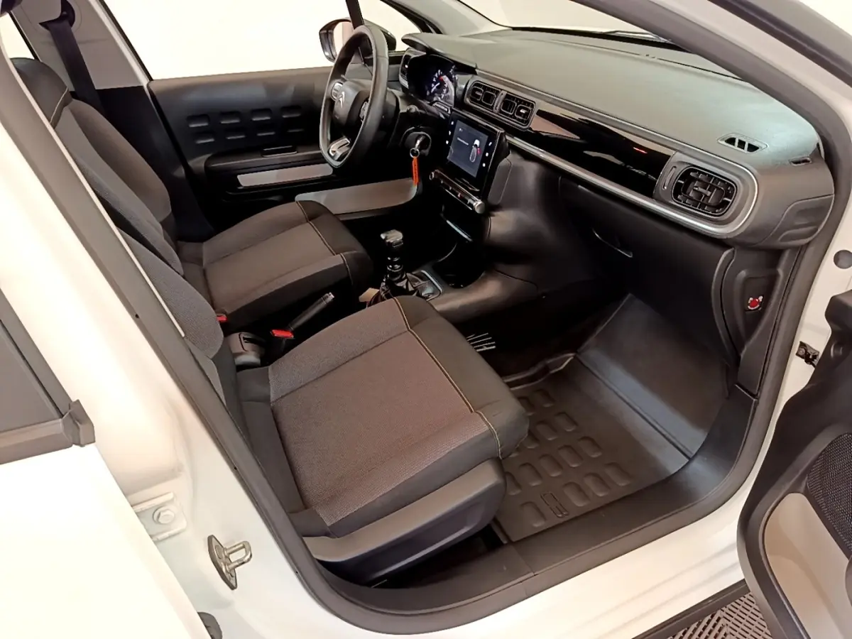 Vue intérieure côté conducteur d'une Citroën C3 blanche 2021, montrant sièges noirs et tableau de bord avec écran tactile.
