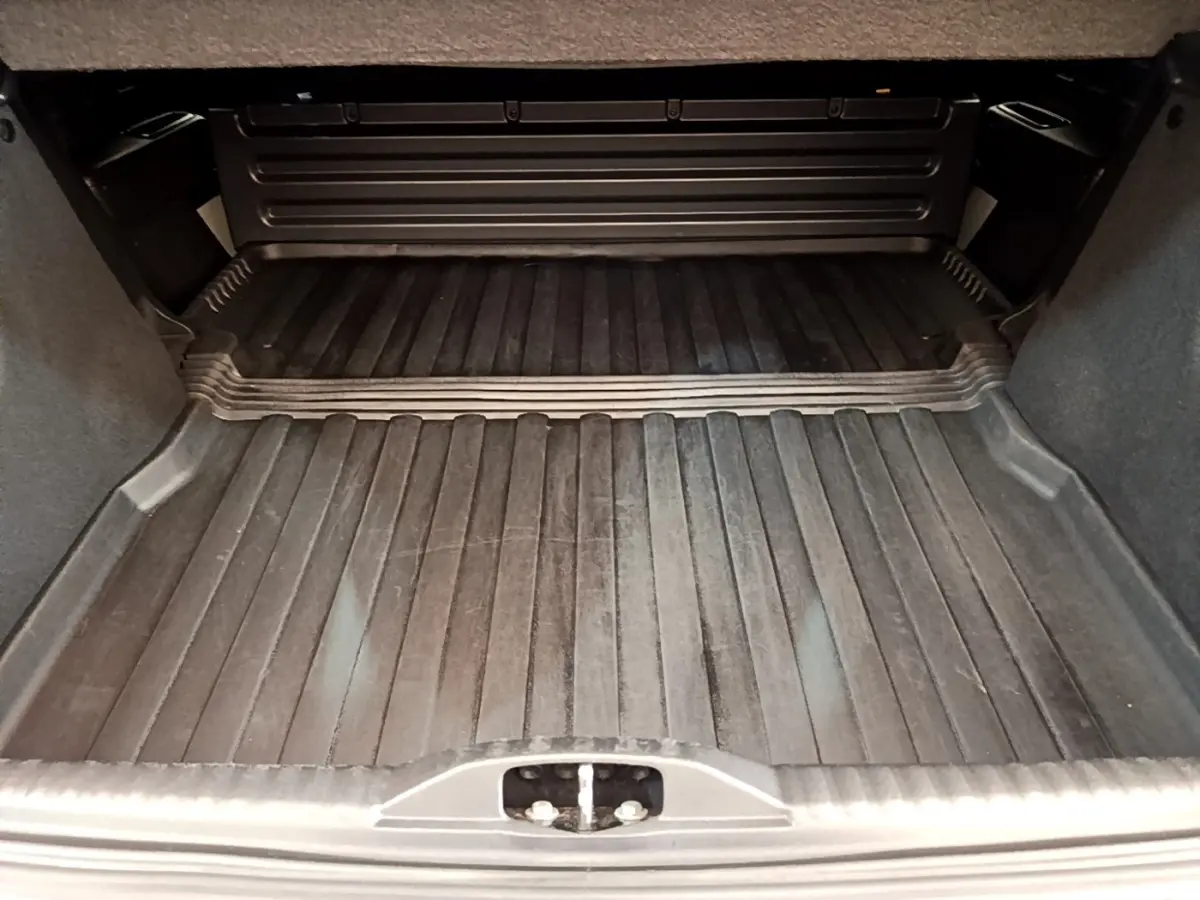 Coffre ouvert d'une Citroën C3 blanche 2021, vue intérieure montrant le tapis de coffre noir et les parois grises.