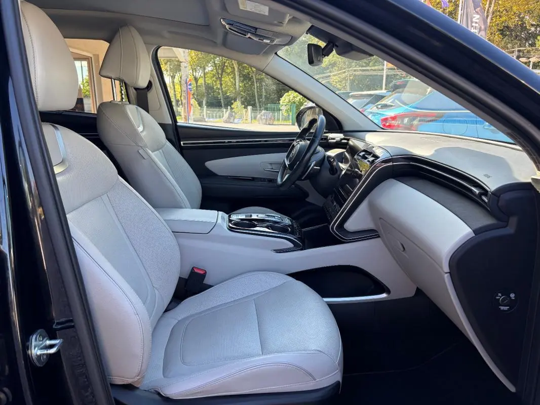 Vue intérieure côté conducteur du Hyundai Tucson noir 2022, sièges clairs et console centrale avec volant cuir.