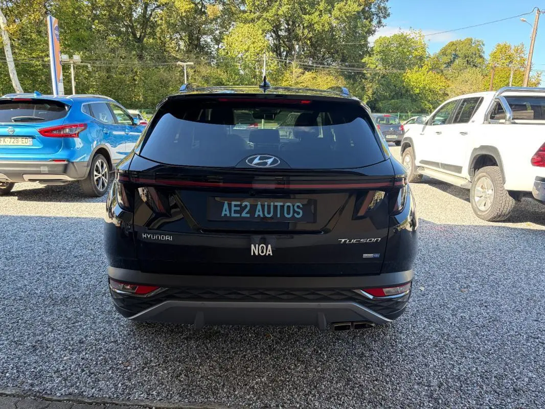 Vue arrière d'un Hyundai Tucson noir 2022 avec feux LED et double sortie d'échappement, stationné sur un sol gravillonné.