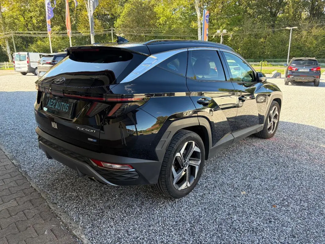 Vue 3/4 arrière droite d’un Hyundai Tucson noir 2022 avec barres de toit et jantes alliage modernes.
