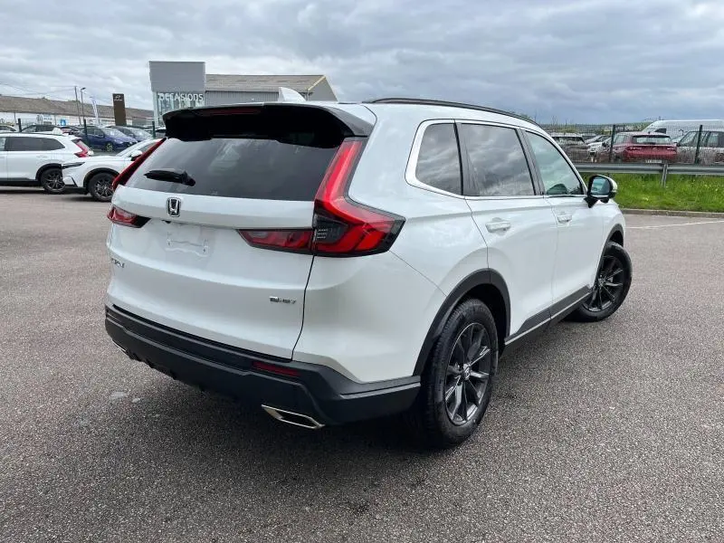 Vue 3/4 arrière droite du Honda CR-V 2024 blanc platine nacré avec jantes noires et feux arrière LED en forme de L.