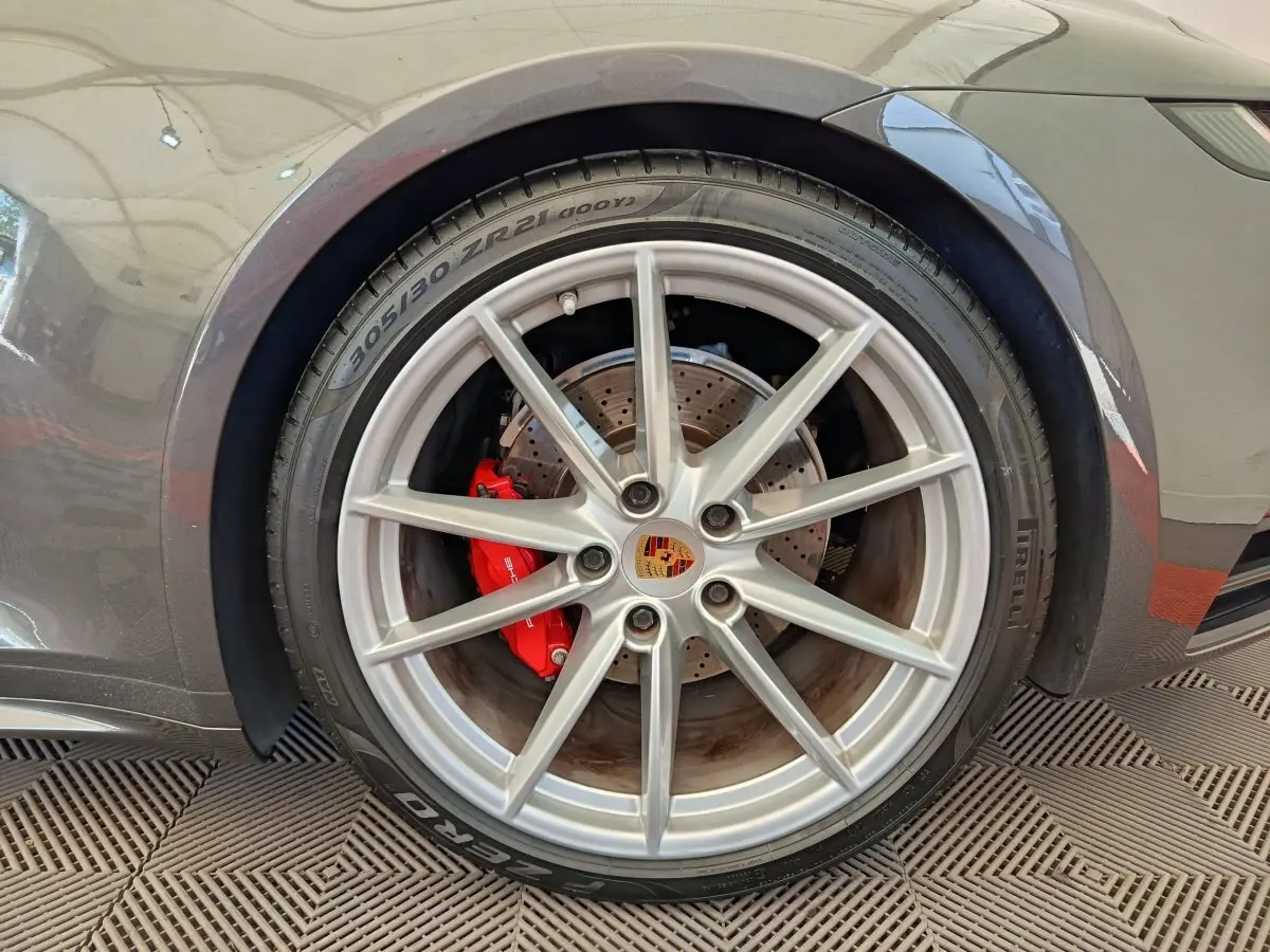 Gros plan sur la roue arrière droite grise d'une Porsche 911 Carrera 4S avec étrier de frein rouge visible.