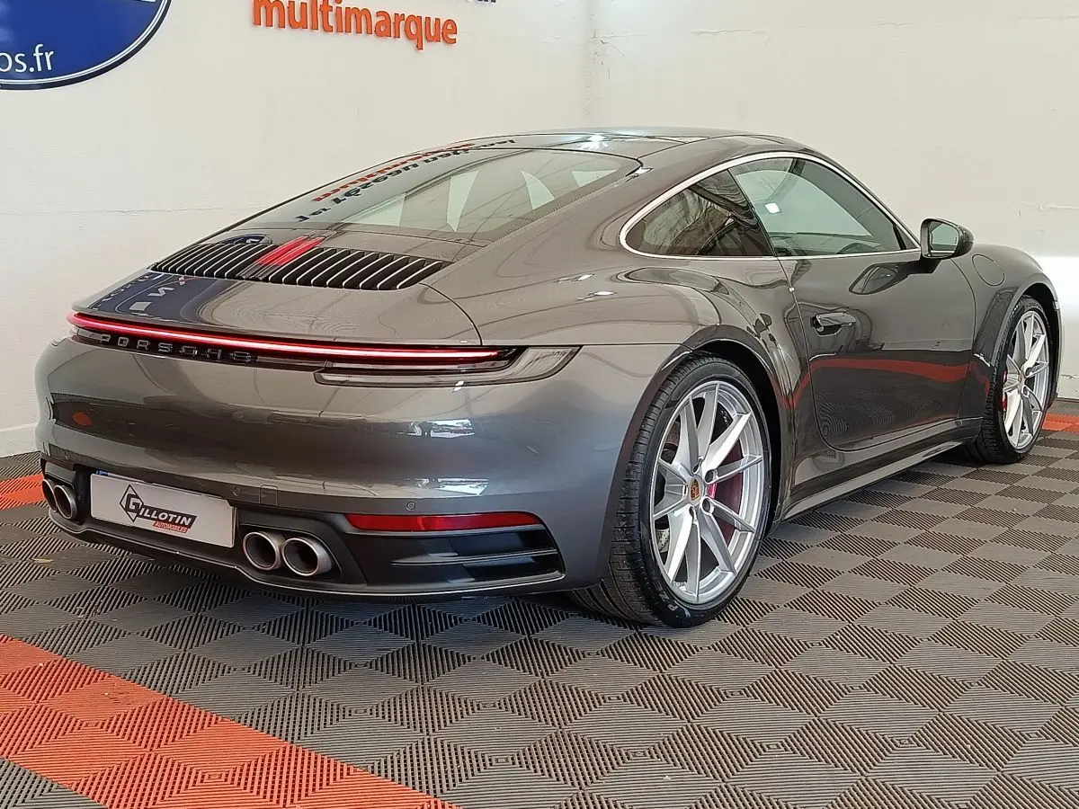 Vue 3/4 arrière droite d'une Porsche 911 Carrera 4S Coupé gris foncé avec feux LED et quadruple sortie d'échappement.