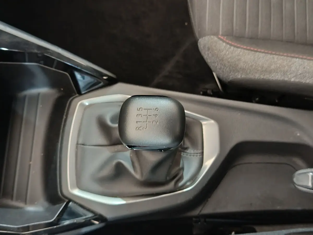 Le levier de vitesses manuel noir de la Peugeot 208 PureTech 100 vue de dessus, avec console centrale grise.