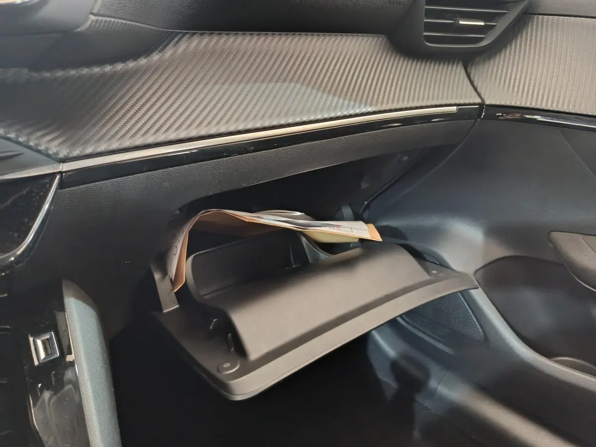 Gros plan sur la boîte à gants ouverte côté passager du Peugeot 208 2020 avec tableau de bord noir texturé.