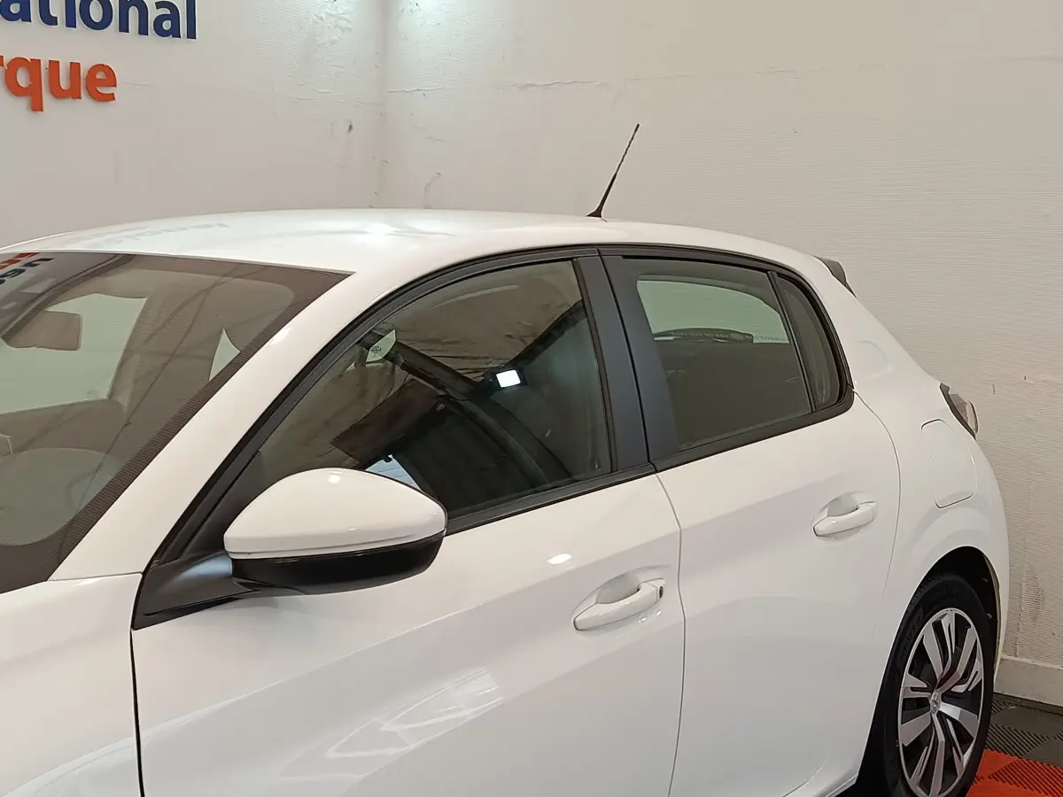 Profil côté gauche d'une Peugeot 208 blanche PureTech 100 S&S Active Business, avec rétroviseur et poignées visibles.