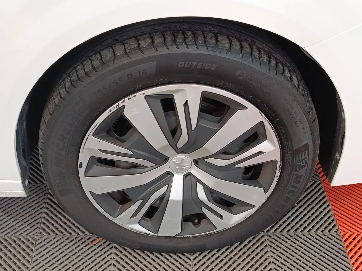 Gros plan sur la roue avant gauche blanche d'une Peugeot 208 PureTech 100 S&S Active Business avec jante stylisée.