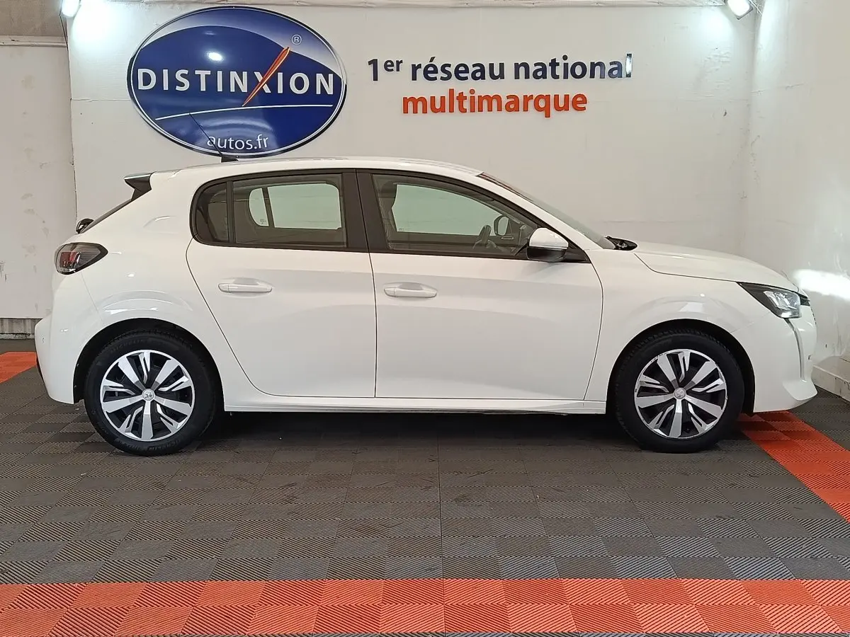 Profil côté gauche d'une Peugeot 208 blanche PureTech 100 S&S Active Business, avec jantes alliage et feux arrière foncés.