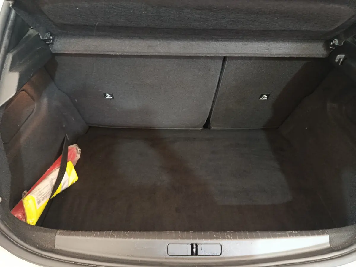Coffre ouvert noir de la Peugeot 208 blanche 2020, avec kit de sécurité visible sur le côté gauche.