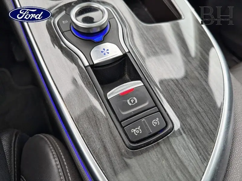 Gros plan sur la console centrale en finition bois gris avec commandes électroniques et éclairage bleu subtil.