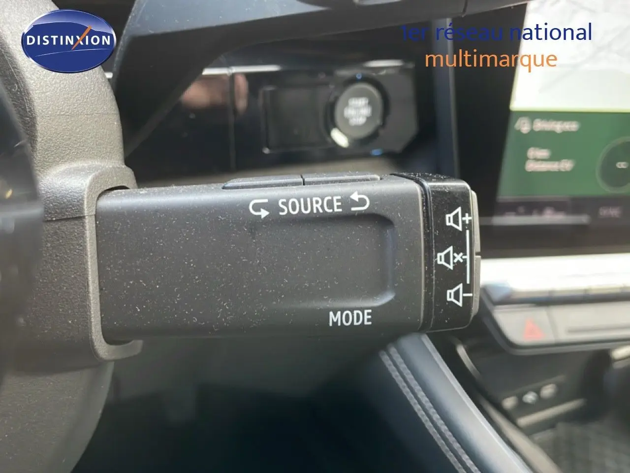 Gros plan sur la commande audio au volant du Renault Espace gris schiste, avec tableau de bord et écran tactile en arrière-plan.