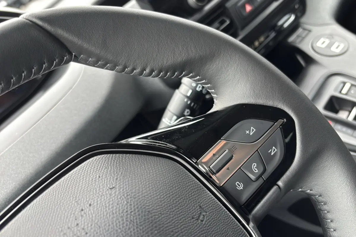 Gros plan sur le volant cuir multifonctions du Peugeot Rifter 2025, mettant en valeur les commandes audio et téléphone.