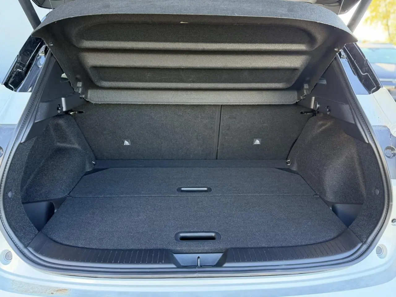 Coffre ouvert du Nissan Qashqai blanc nacré, vue arrière montrant un plancher de coffre plat et modulable.