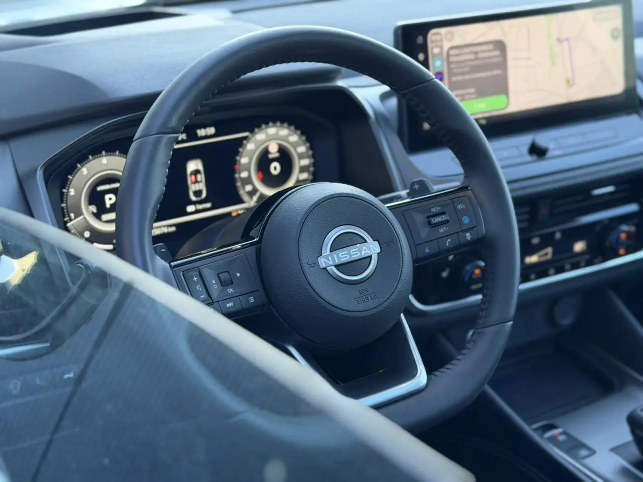 Vue rapprochée du volant cuir noir et du combiné numérique du Nissan Qashqai 2025 avec écran tactile et affichage tête haute.