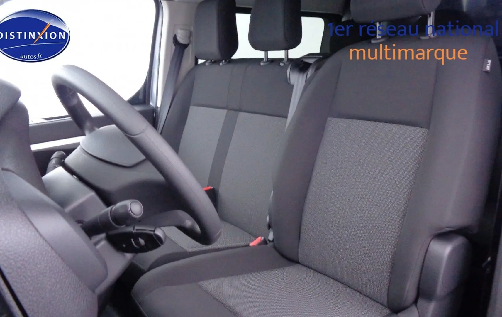 Vue intérieure côté conducteur du Peugeot Expert Long 2023, sièges tissu gris noir et volant simple noir.