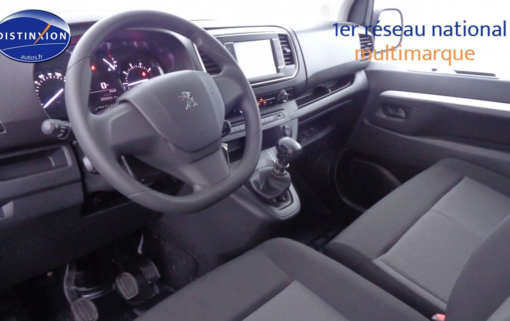 Intérieur avant droit du Peugeot Expert Long 2023, montrant le volant, la boîte manuelle et les sièges gris tissu.