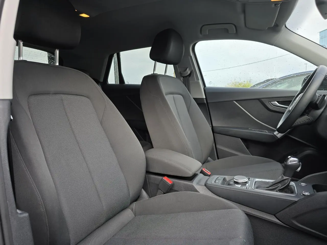 Vue intérieure côté droit de l'Audi Q2 2023 avec sièges tissu gris et console centrale équipée d'une boîte automatique.