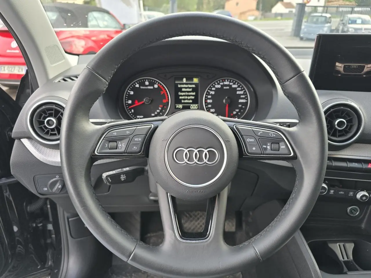 Volant cuir multifonction Audi Q2 35 TFSI 2023 vu de face avec tableau de bord et compteurs analogiques.